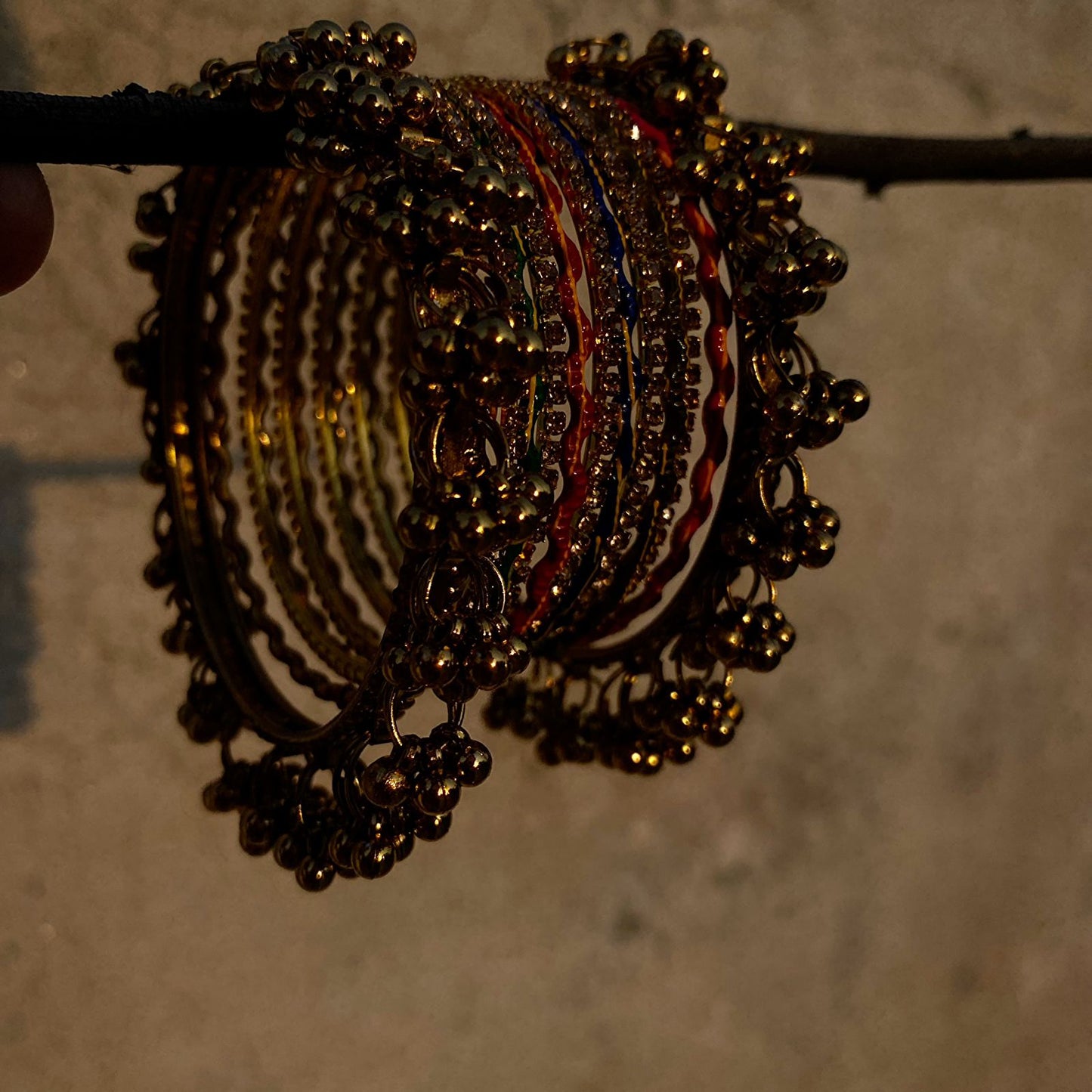 The Ghungroo Border: Framing the set are wide, golden bangles adorned with a dense fringe of tiny, polished bells (ghungroos).