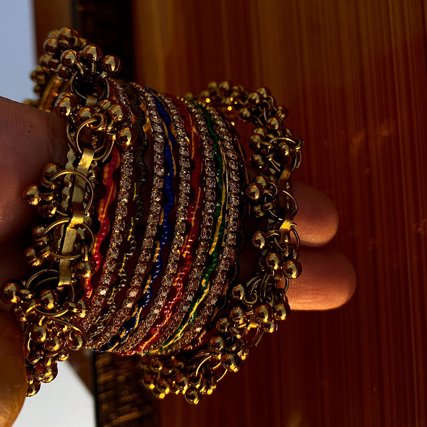 The Ghungroo Border: Framing the set are wide, golden bangles adorned with a dense fringe of tiny, polished bells (ghungroos).