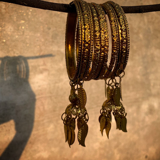 A set of antique-style gold bangles that blend traditional craftsmanship with whimsical design elements.