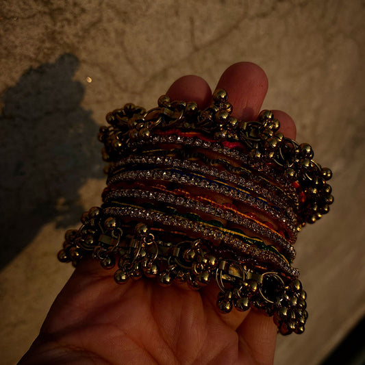 The Ghungroo Border: Framing the set are wide, golden bangles adorned with a dense fringe of tiny, polished bells (ghungroos).